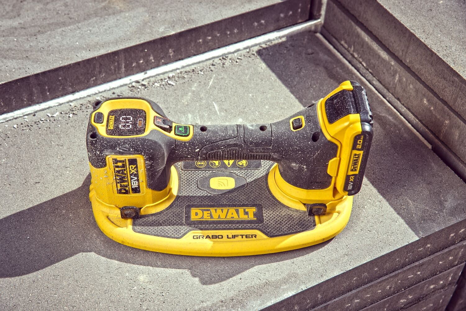 DEWALT Grabo Lifter tool rests on concrete stair, black and yellow, dust-covered, used for material lifting.