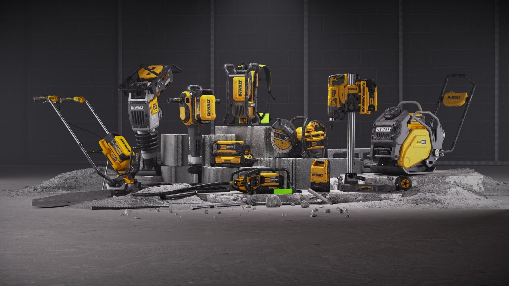 A collection of yellow and black DEWALT construction tools is displayed on concrete blocks and a dusty floor. The assortment includes power tools such as a compactor, demolition hammer, chainsaw, and other cordless equipment, all arranged in a studio setting with a dark background.